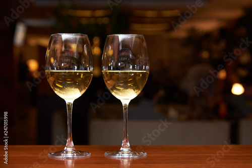 Two glasses of white wine with a reflection on the bar.