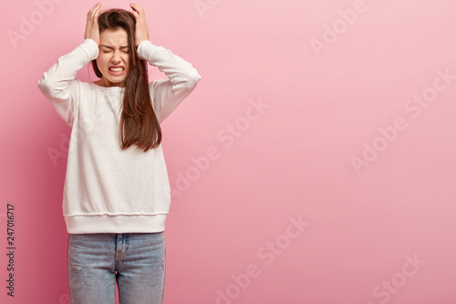 Indoor shot of frustrated European woman feels intense, suffers from pain, fe...