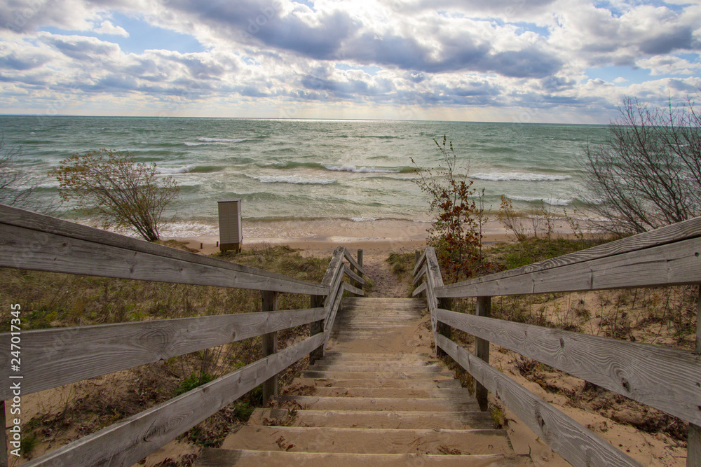 Wooden Stairs To Beach. Long wooden staircase leads to a sunny sandy beach on the Michigan coast of Lake Michigan.
