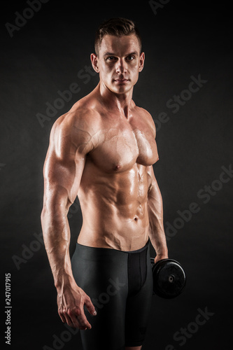 Athletic shirtless young male fitness model with dumbbells
