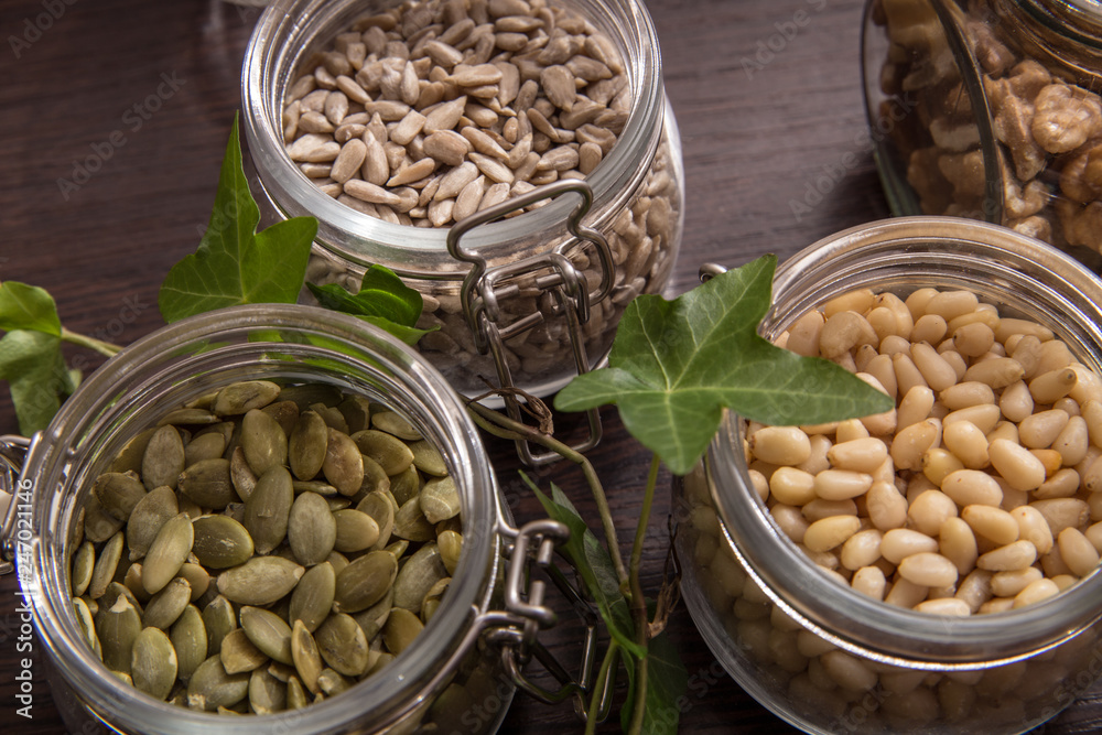 Cedar, sunflower seeds, pumpkins in jars on the table among the plants Cedar, sunflower seeds, pumpkins in jars on the table among the plants