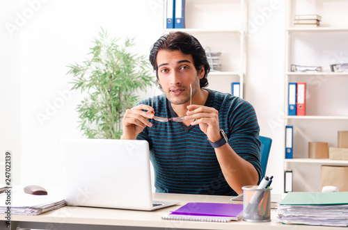 Young handsome male employee sitting at the office