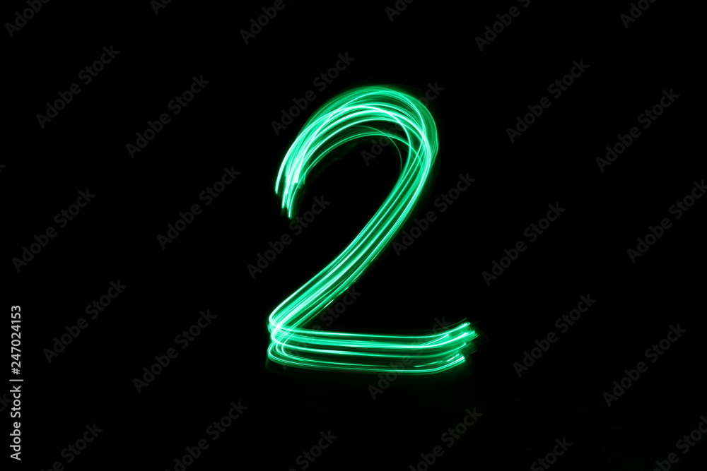 Long exposure, light painting photography.  Single number two in a vibrant neon green colour against a black background - obrazy, fototapety, plakaty 