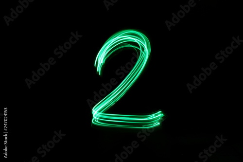 Long exposure, light painting photography.  Single number two in a vibrant neon green colour against a black background