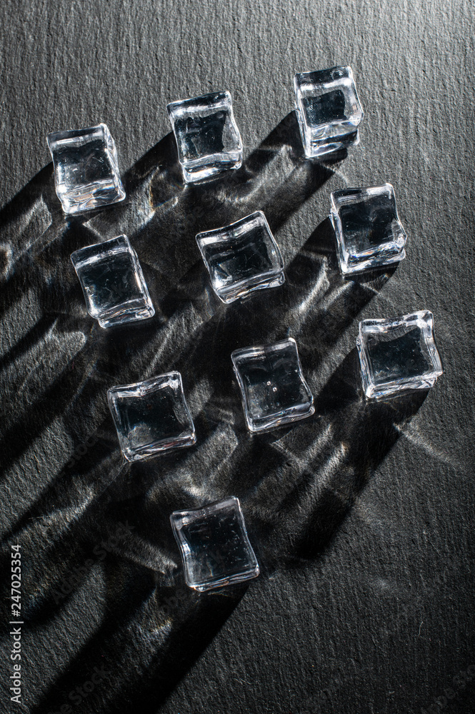 Ice cubes on black stone board. Hard light. Deep shadows. Cold and freshness concept. Ice cubes on black stone board. Hard light. Deep shadows. Cold and freshness concept.