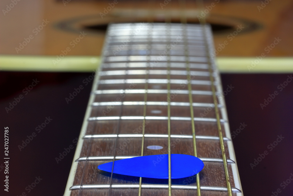 A close up color image of a guitar fret board and strings with a guitar pick in the strings. A close up color image of a guitar fret board and strings with a guitar pick in the strings.