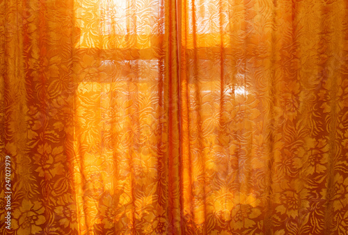 Orange curtains and a window behind a bright day