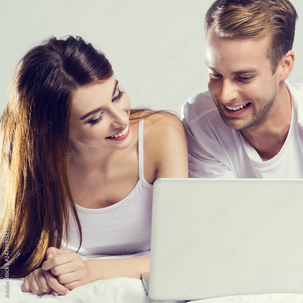 Couple using laptop, on bed Couple using laptop, on bed