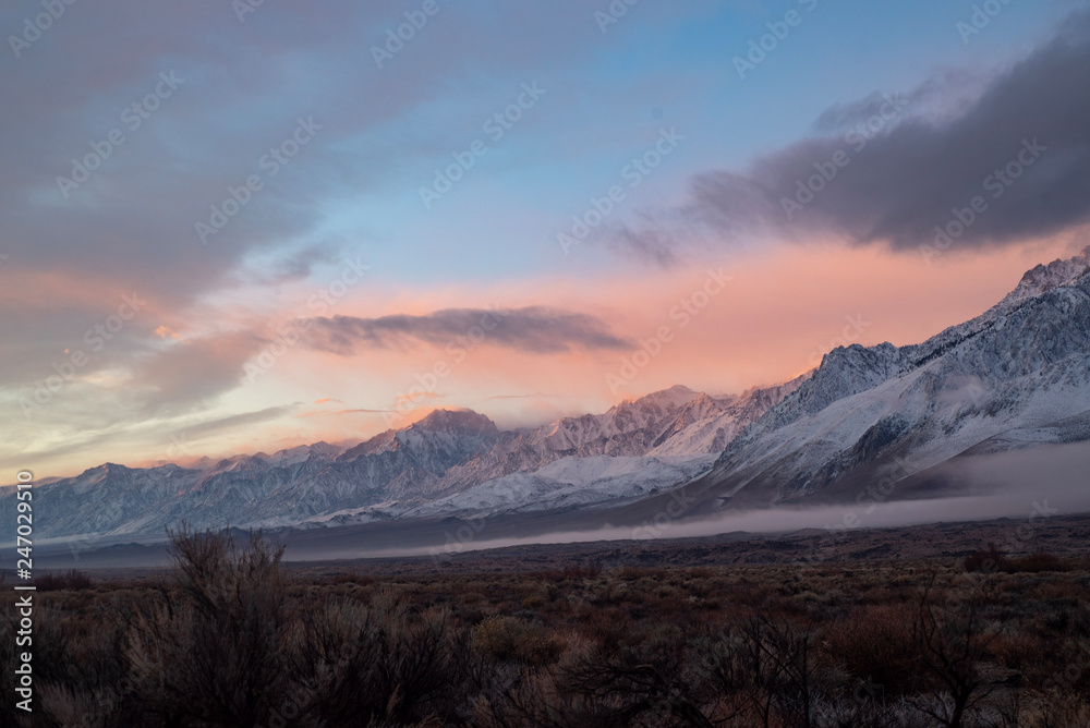 pink sky clouds over snowy mountain range at sunrise