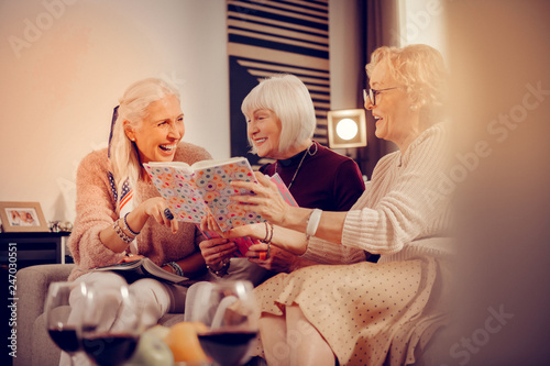 Delighted cheerful nice women enjoying reading books photo