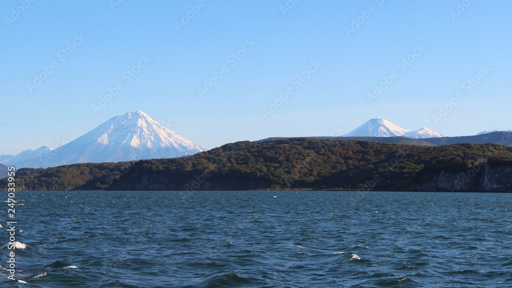 Avachinsky and Koryaksky volcanoes rises above the coastline of the Kamchatka Peninsula. Avachinsky and Koryaksky volcanoes rises above the coastline of the Kamchatka Peninsula.