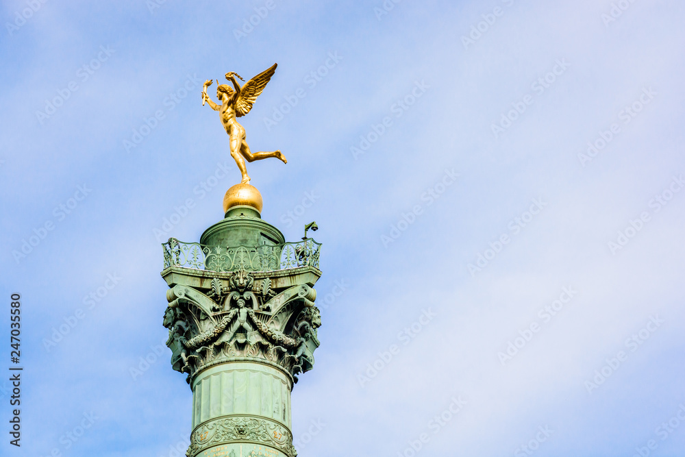 The Genius of Liberty golden statue, by french sculptor Auguste Dumont, atop the July Column in the center of Place de la Bastille in Paris, France, against blue sky.