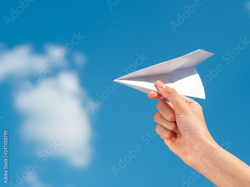 Woman Hand holding paper rocket with blue sky background. freedom concept