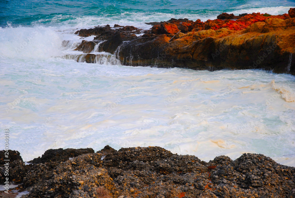 breaking waves at the red rocky coast of Sissi on Crete in Greece