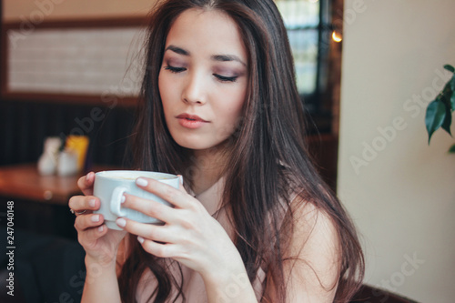 Beautiful charming romantic brunette smiling Asian girl has Breakfast with coffee at cafe