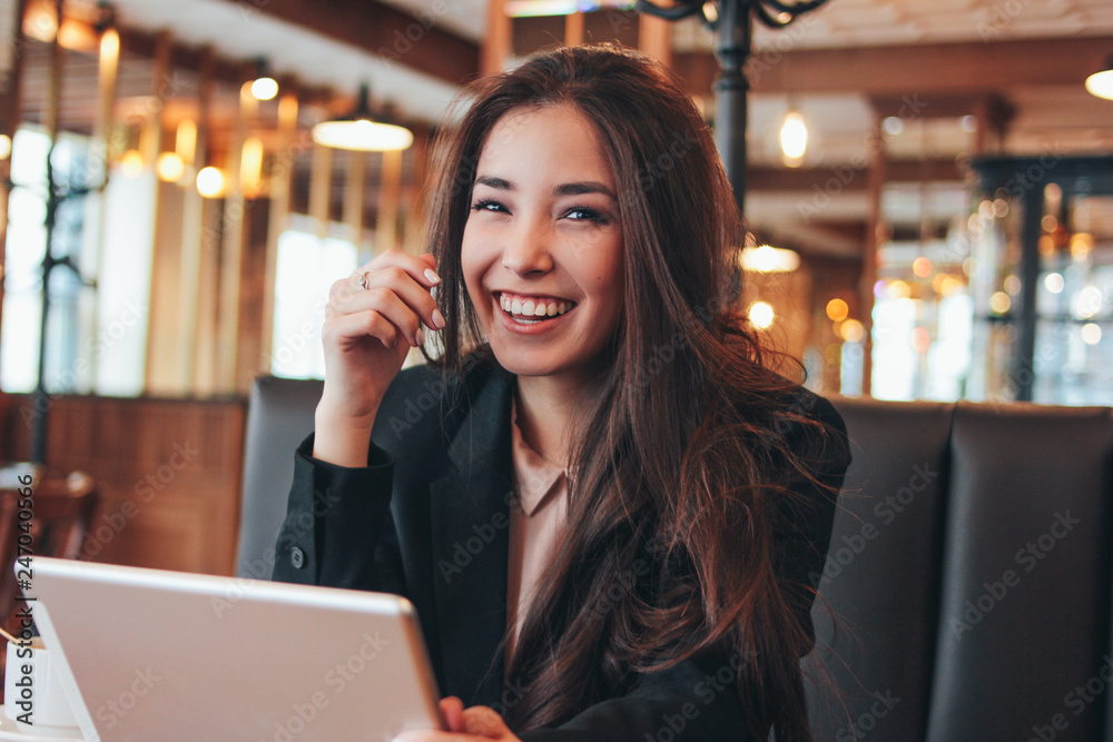 Beautiful charming brunette happy asian girl with tablet at table in cafe, student, freelancer or young manager