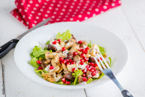 plate of salad with mushrooms, meat and pomegranate seeds