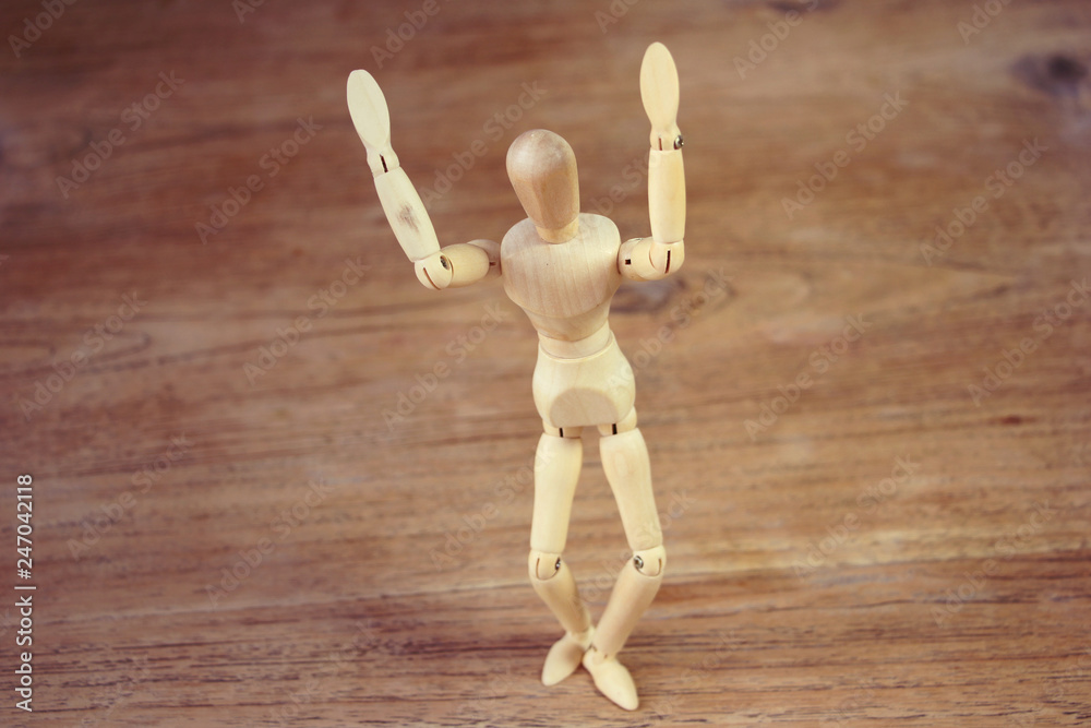 Wooden model showing dramatical pose on darker wooden table background Wooden model showing dramatical pose on darker wooden table background