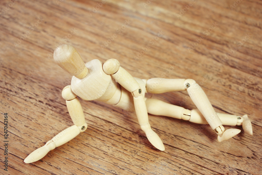 Wooden model showing dramatical pose on darker wooden table background Wooden model showing dramatical pose on darker wooden table background