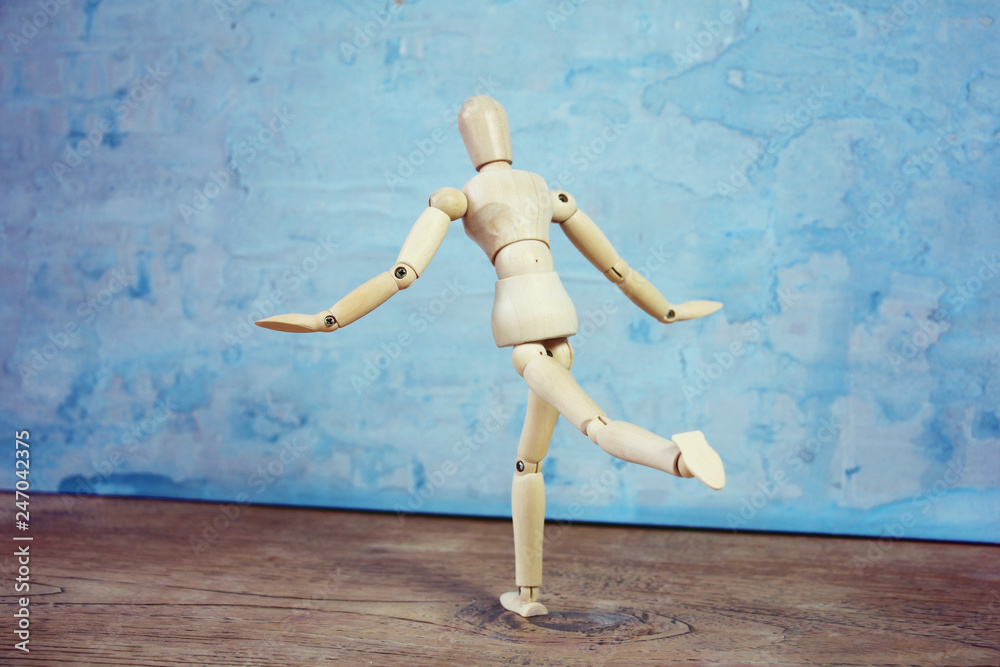 Wooden model showing dramatical pose in front of blue art background Wooden model showing dramatical pose in front of blue art background