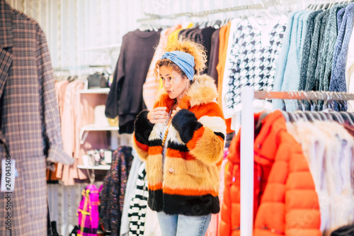 Attractive fashion young beautiful cute woman in a store wearing a ecological natural fur with many colors - modern and chic people in commerce concept - city lifestyle consumism photo