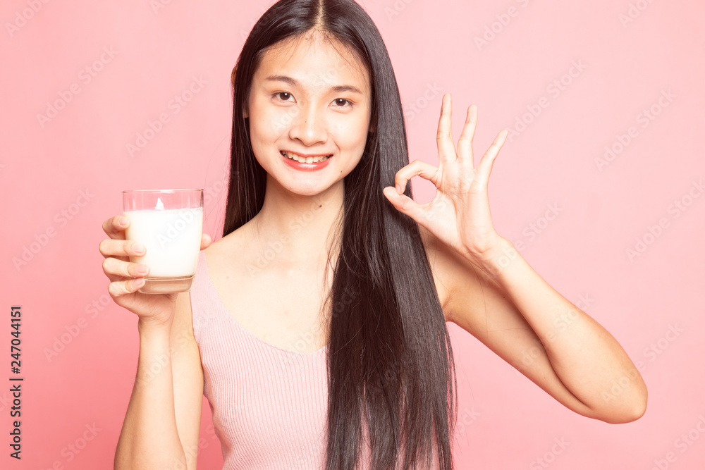 Healthy Asian woman drinking a glass of milk show OK sign. Healthy Asian woman drinking a glass of milk show OK sign.