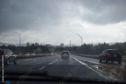 Cars are driving along the highway in rainy foggy weather to the city, which stands among the mountains. Asheville, North Carolina / USA, July 07/2018