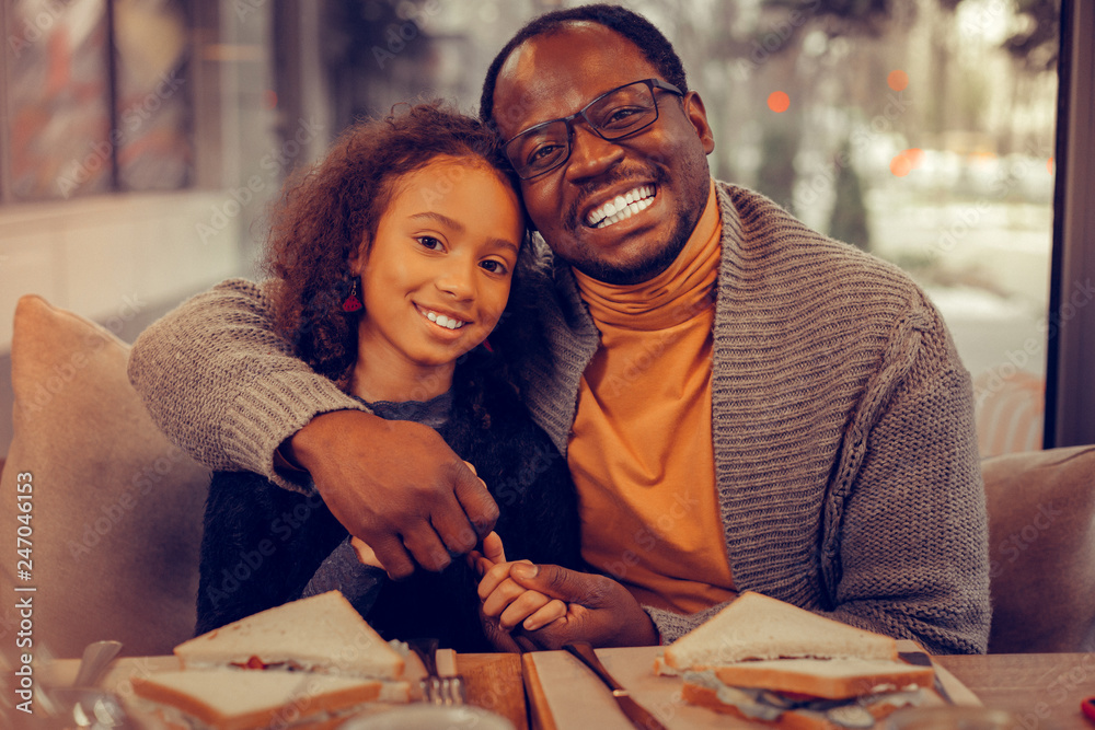 Fototapeta premium Beaming father smiling broadly while hugging his daughter