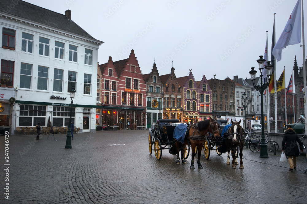Bruges/Belgium - December 31 / 2016  :  Horse carts are wating for the customers in front of historical houses at Markt square