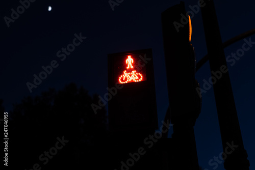 Traffic light with red lights for pedestrians and cyclists, with figure of a cyclist. Night background for the concept of stopping in a friendly city with cyclists.