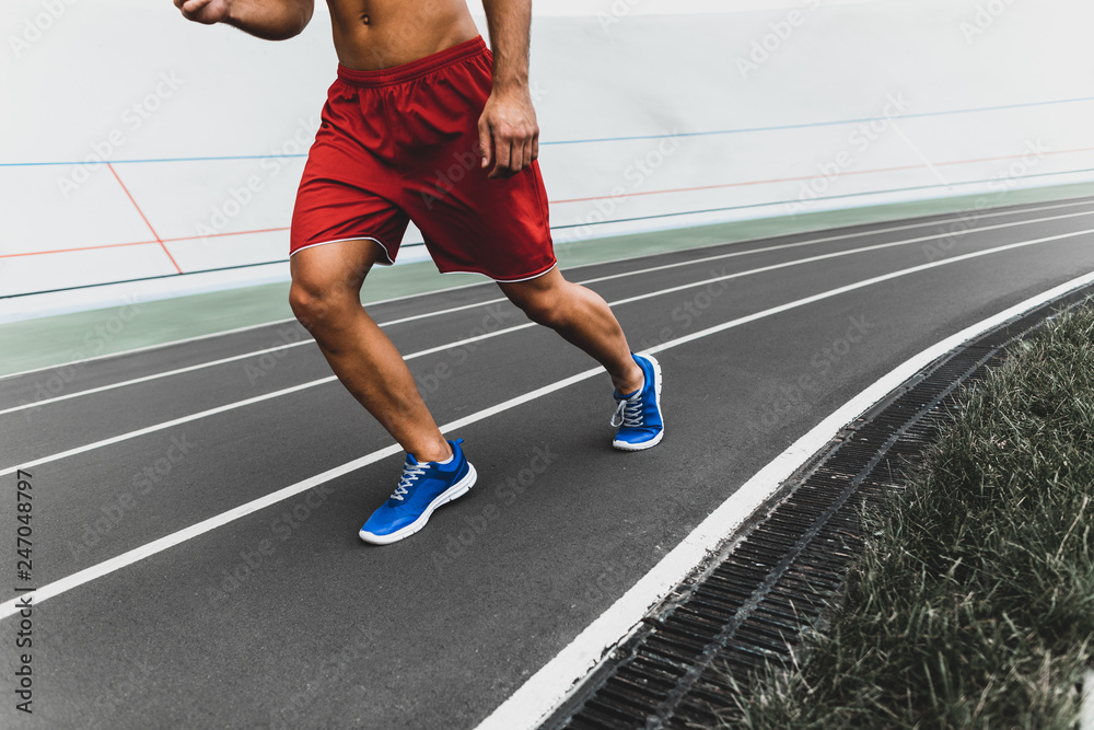 Fototapeta premium Bare-chested young guy moving during training outside