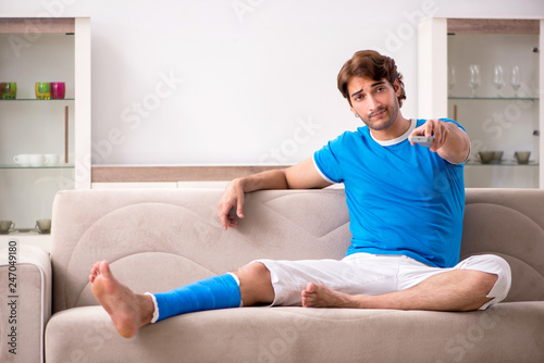 Leg injured young man on the sofa