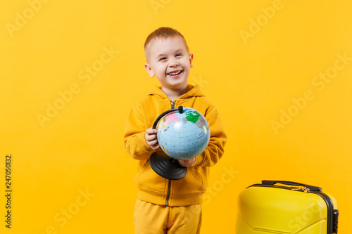 Little traveler tourist kid boy 3-4 years old isolated on yellow orange wall background studio. Passenger traveling abroad to travel on weekends getaway. Air flight journey concept. Mock up copy space