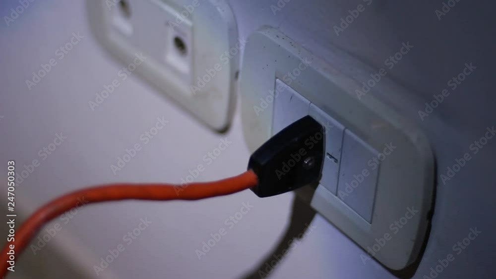 Man Hand plugging in Power Plug on White Electrical Outlet Mounted on Wall during a Power Outage. Close Up. Man Hand plugging in Power Plug on White Electrical Outlet Mounted on Wall during a Power Outage. Close Up.