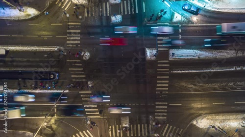 Loopable 4K aerial timelapse of a busy intersection at night.. Aerial top-down view of a junction with heavy rush hour city traffic with pedestrians, cars, trams and buses 