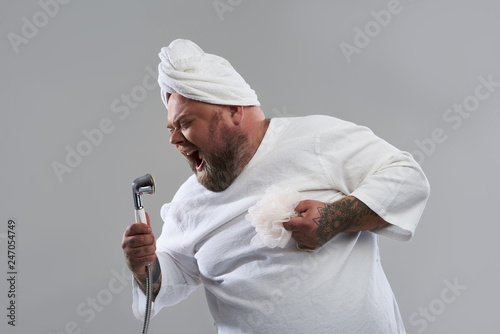 Waist up of fat man singing into the shower head