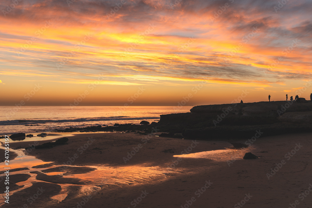 Sky reflection in water pool flowing to the ocean at Carcavelos beach at sunset