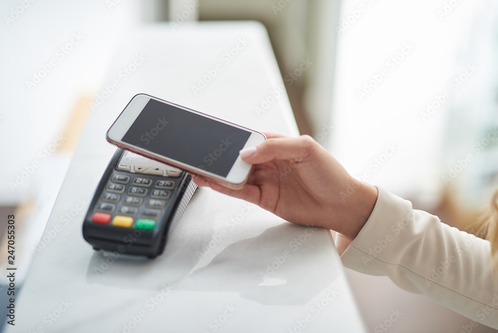 Young woman paying with NFC technology on mobile phone