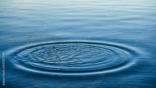 Ripples on sea texture pattern background. Round droplets of water over circles on pool water. Fresh water drop, whirl and splash. Laptop decorative wallpaper. Bright water rings affect the surface.
