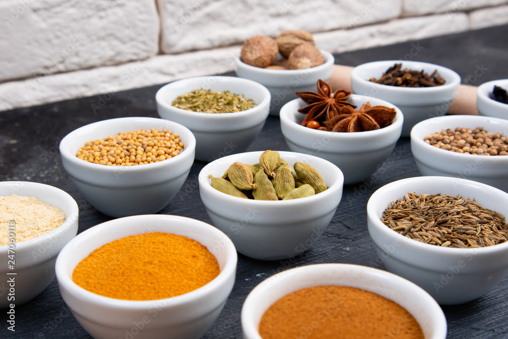 Various spices in bowls on a black slate board. Spices background