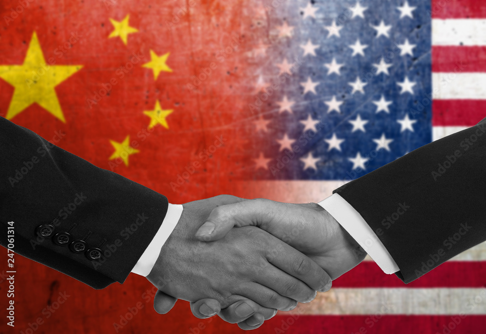Two men/politicians in suits shaking hands with the national flags on the background - China and United States