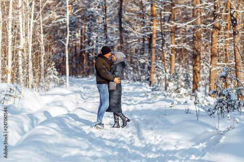 A happy couple with a dog (black Labrador) having fun outside in the forest on a sunny frosty winer day.