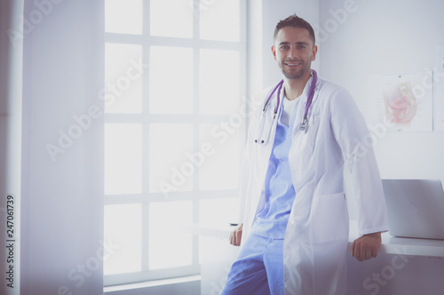 Young and confident male doctor portrait standing in medical office. photo