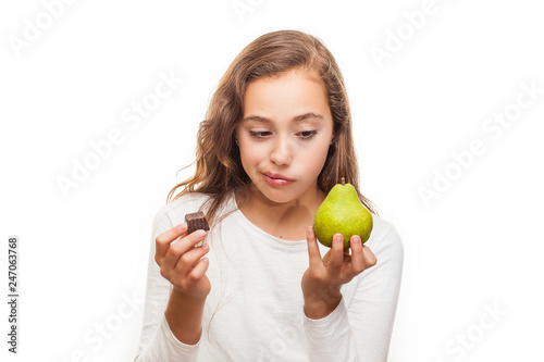 Young girl choosing between fruit and chocolate isolated on white background