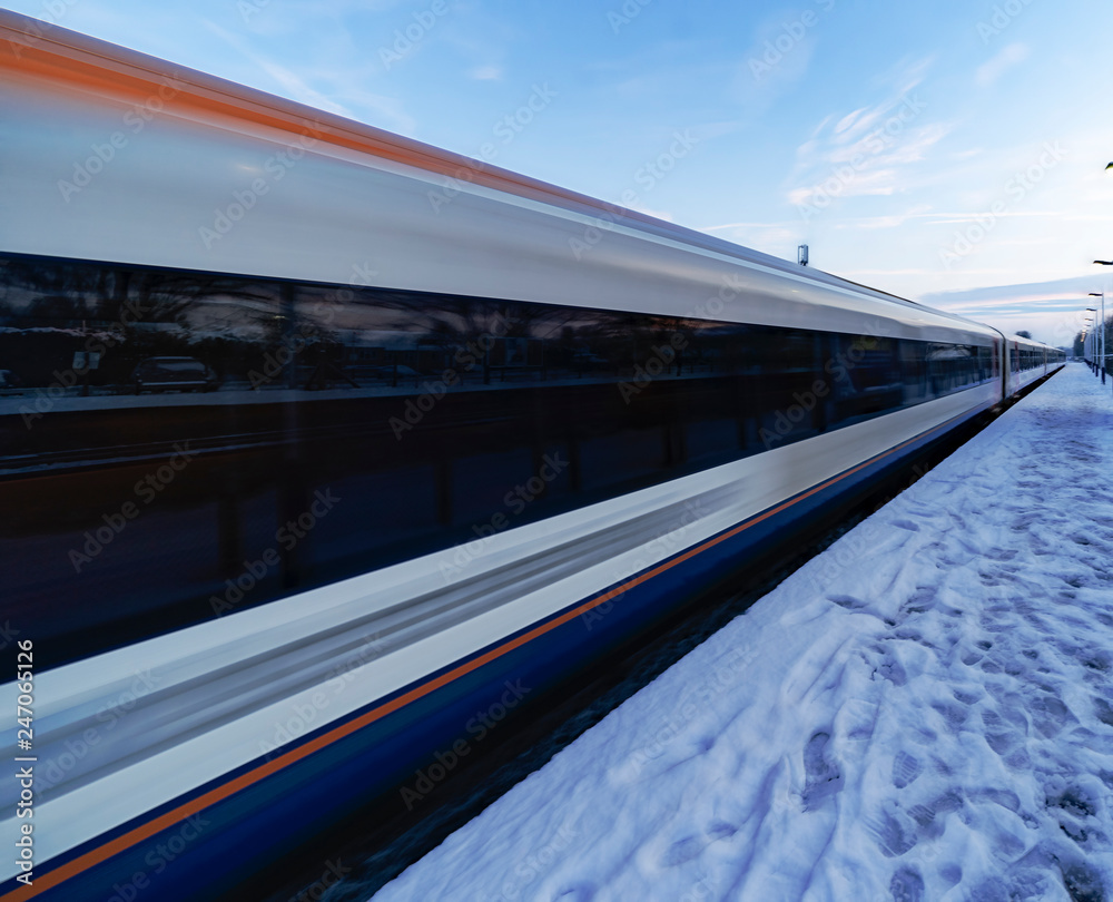 Fototapeta premium Train departing a UK station at speed in the snow