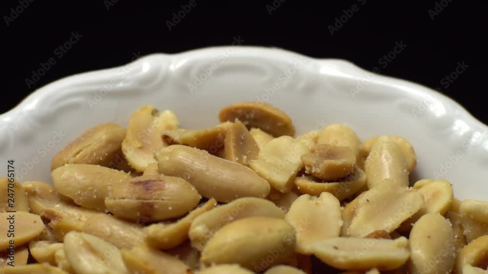 Peanuts. Peeled peanuts fried with salt. Rotation. Snack closeup. Peanuts in a bowl. Selective focus. black background. Studio shot. Peanuts. Peeled peanuts fried with salt. Rotation. Snack closeup. Peanuts in a bowl. Selective focus. black background. Studio shot.