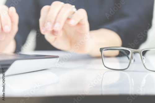 Eine Frau arbeitet und hat eine Brille neben einem Laptop auf den Schreibtisch gelegt. 