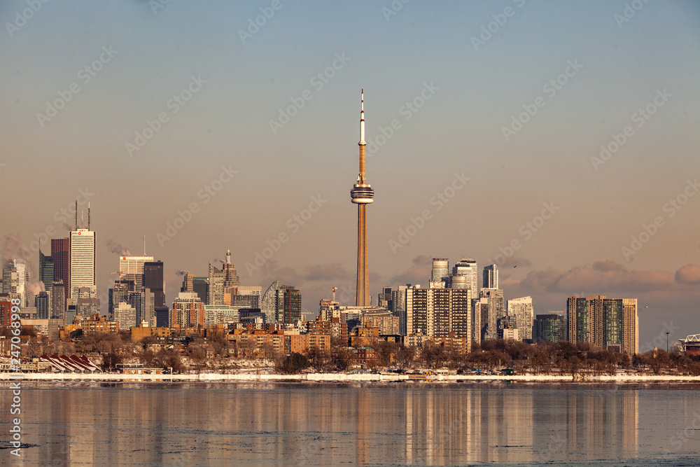 Obraz premium Toronto, CANADA - February 1th, 2019: Panoramic Canadian winter landscape near Toronto, beautiful frozen Ontario lake at sunset. Scenery with winter trees, water and blue sky.