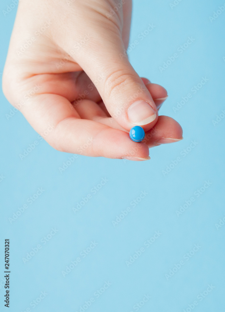 Close-up shot of capsule in nurse's hand isolated over blue background Close-up shot of capsule in nurse's hand isolated over blue background