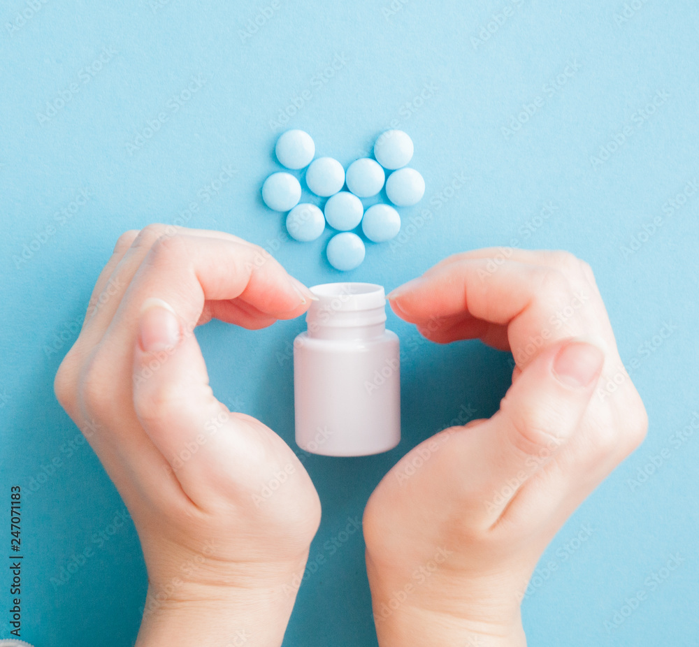 Woman's hands created a heart shape. White pills. Mock up for special offers as advertising or other ideas. Medical and healthcare concept. Copy space. Empty place for text or logo on blue background Woman's hands created a heart shape. White pills. Mock up for special offers as advertising or other ideas. Medical and healthcare concept. Copy space. Empty place for text or logo on blue background